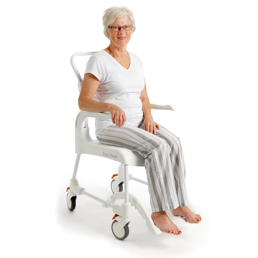 Demonstration of removing the commode pan or adjusting the height on Etac Clean Shower Commode Chair.