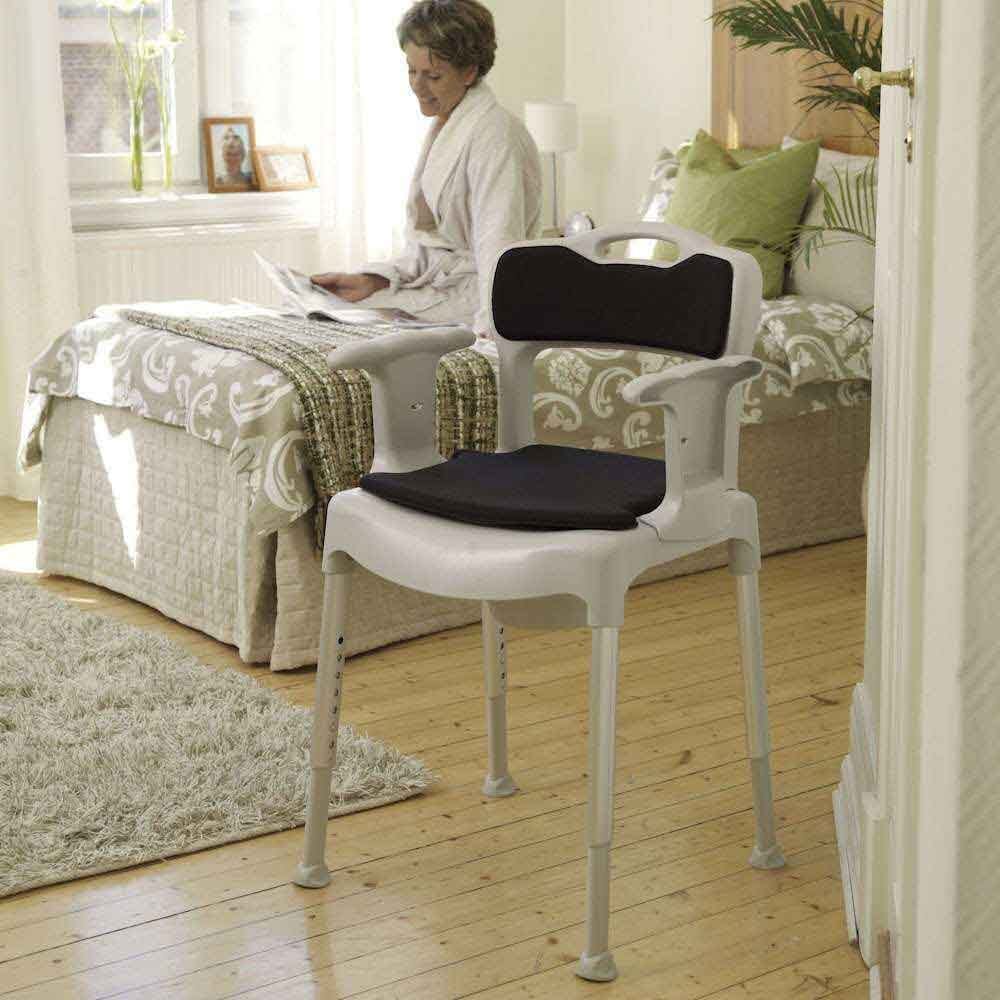 Etac Swift Commode positioned in a home environment such as a bedroom or bathroom, demonstrating its discreet appearance.