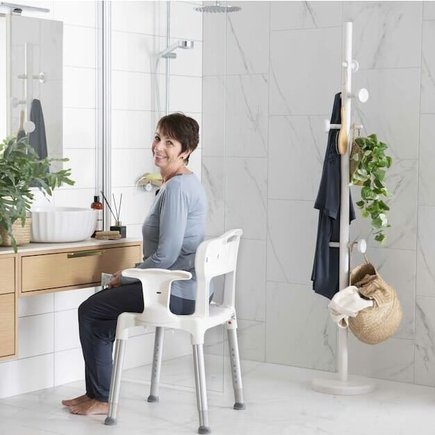 Front view of Etac Swift Shower Chair with Arm Supports showing drainage holes in the seat and the supportive backrest design.