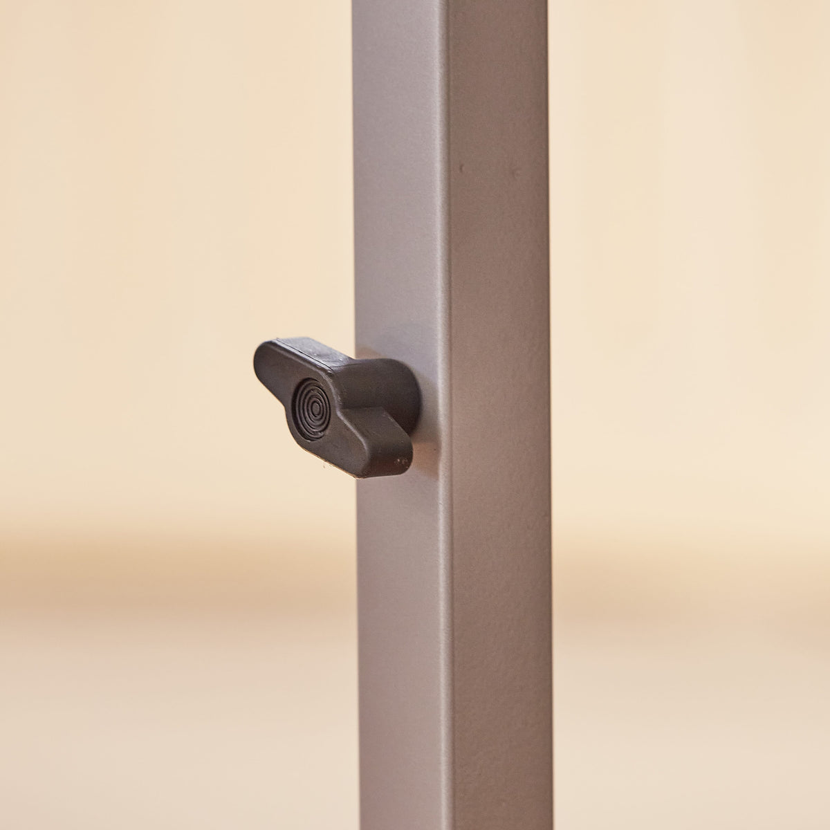 Close-up of a push button or knob on NRS Adjustable Overbed Table's frame used for adjusting height or tilt.