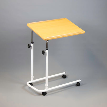 Angled view of NRS Beech Overbed Overchair Table with beech-effect tilting table top and white U-shaped base on castors against a neutral background.