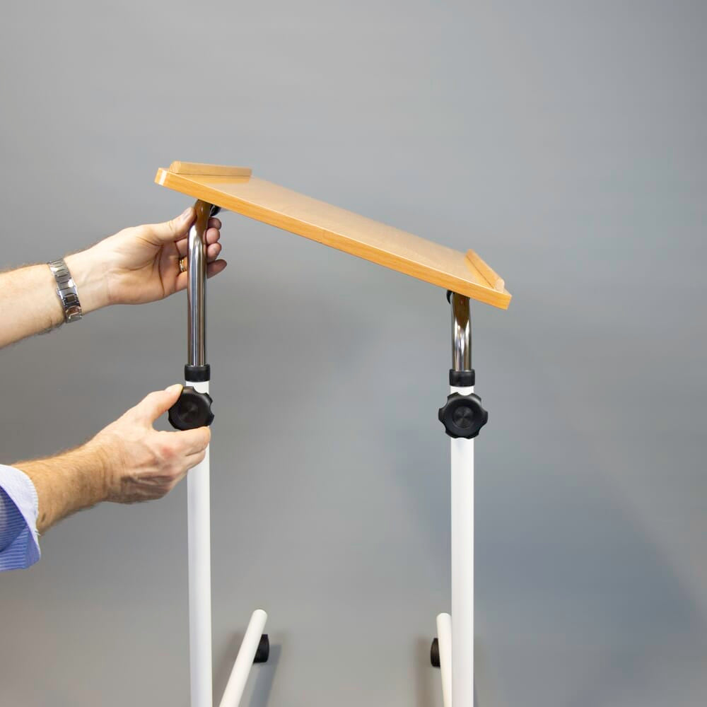 Close-up of hands adjusting the height or tilt of NRS Beech Overbed Overchair Table, showing the easy-turn knobs.