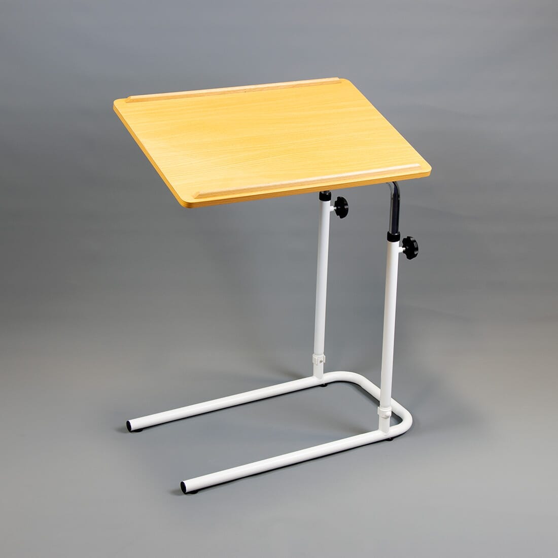 Front view of NRS Beech Overbed Overchair Table with the table top tilted, showing the raised lips and attractive beech finish.