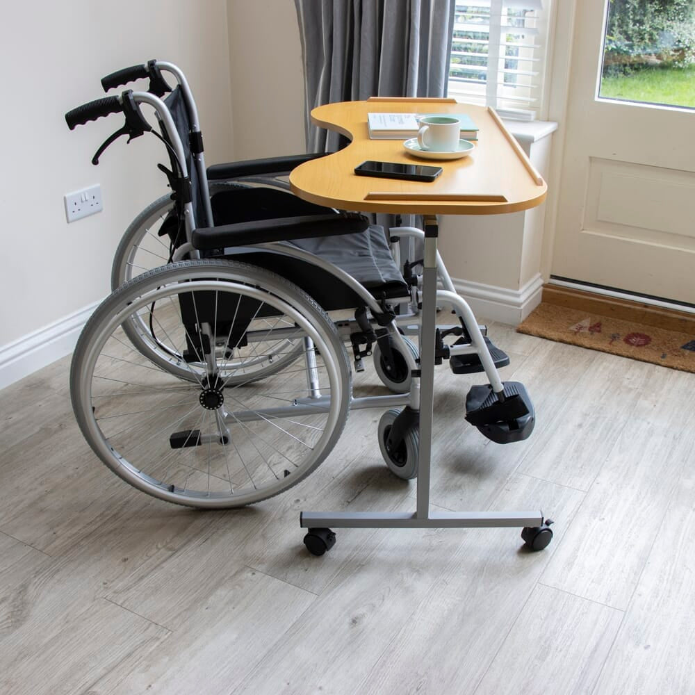 Side view of NRS Curved Adjustable Overbed Table showing the tilting top and height-adjustable chrome stems.