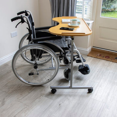 Side view of NRS Curved Adjustable Overbed Table showing the tilting top and height-adjustable chrome stems.