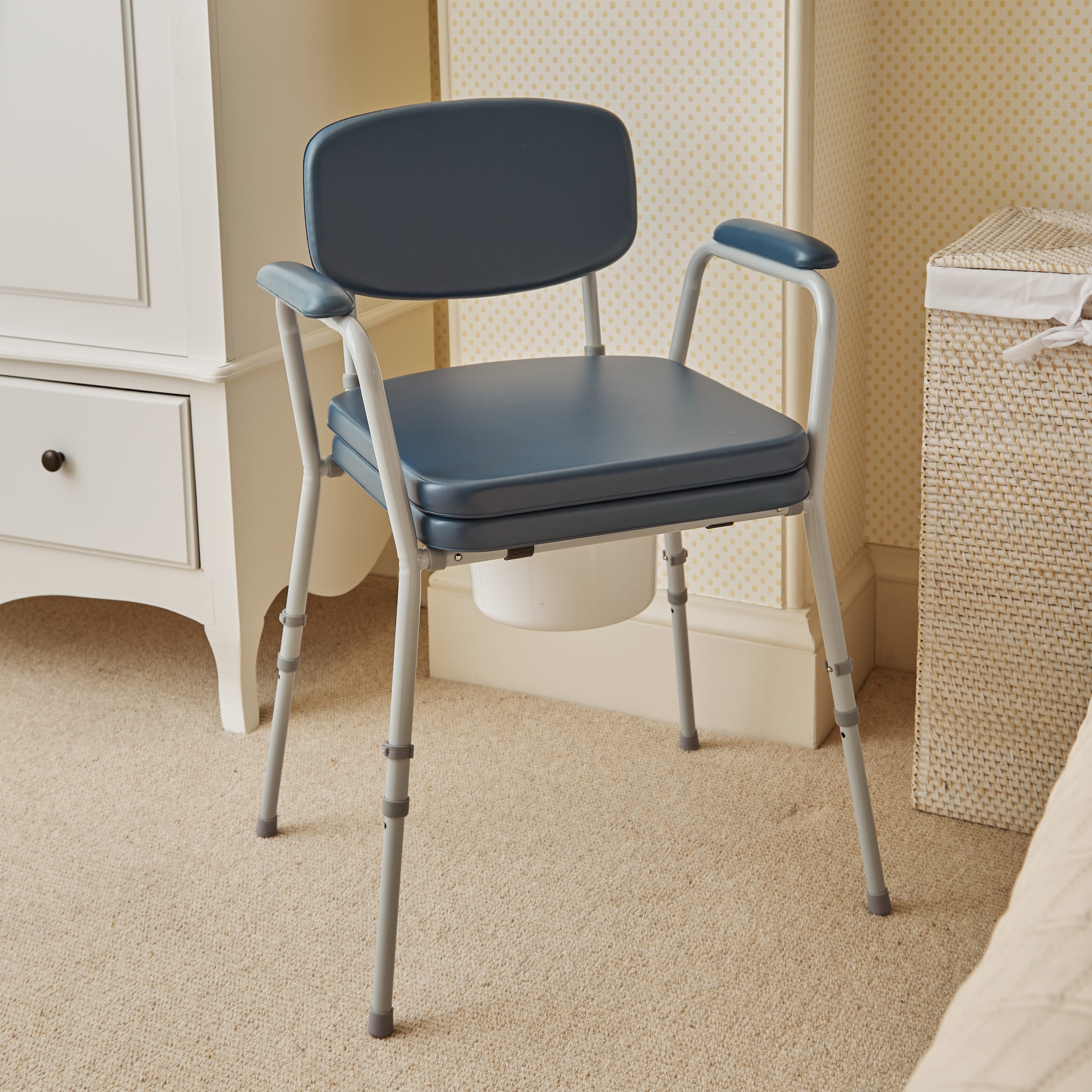 NRS Dovedale Comfort Commode with lid raised showing the open seat and removable commode pan, with supportive arms and adjustable height on a plain background.