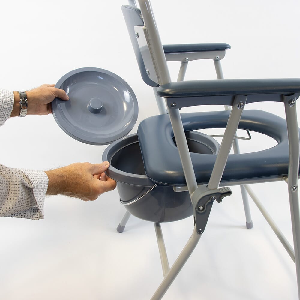 Person emptying or cleaning the commode pan of NRS Dovedale Folding Commode into a standard toilet.