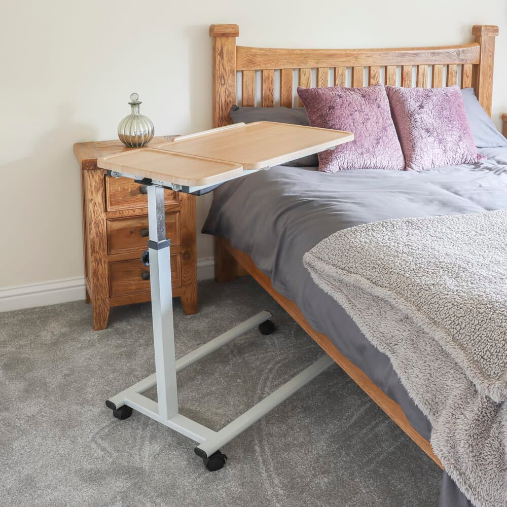 Side view of NRS Easylift Home Tilting Overbed Table showing the tilting top and height-adjustable chrome stems.
