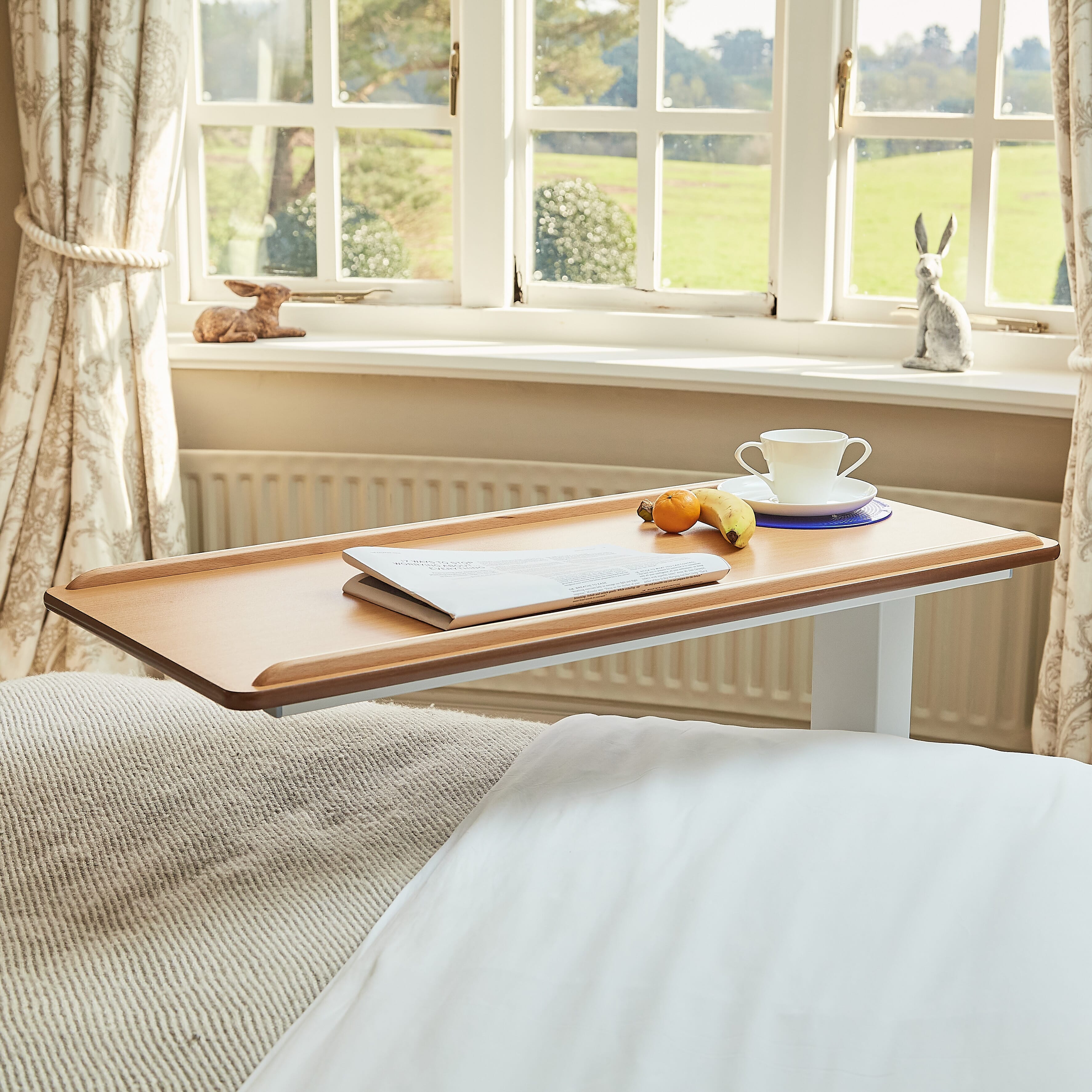 Close-up of hands adjusting the height or tilt of NRS Easylift Overbed Table-Low, showing the easy-turn knobs.