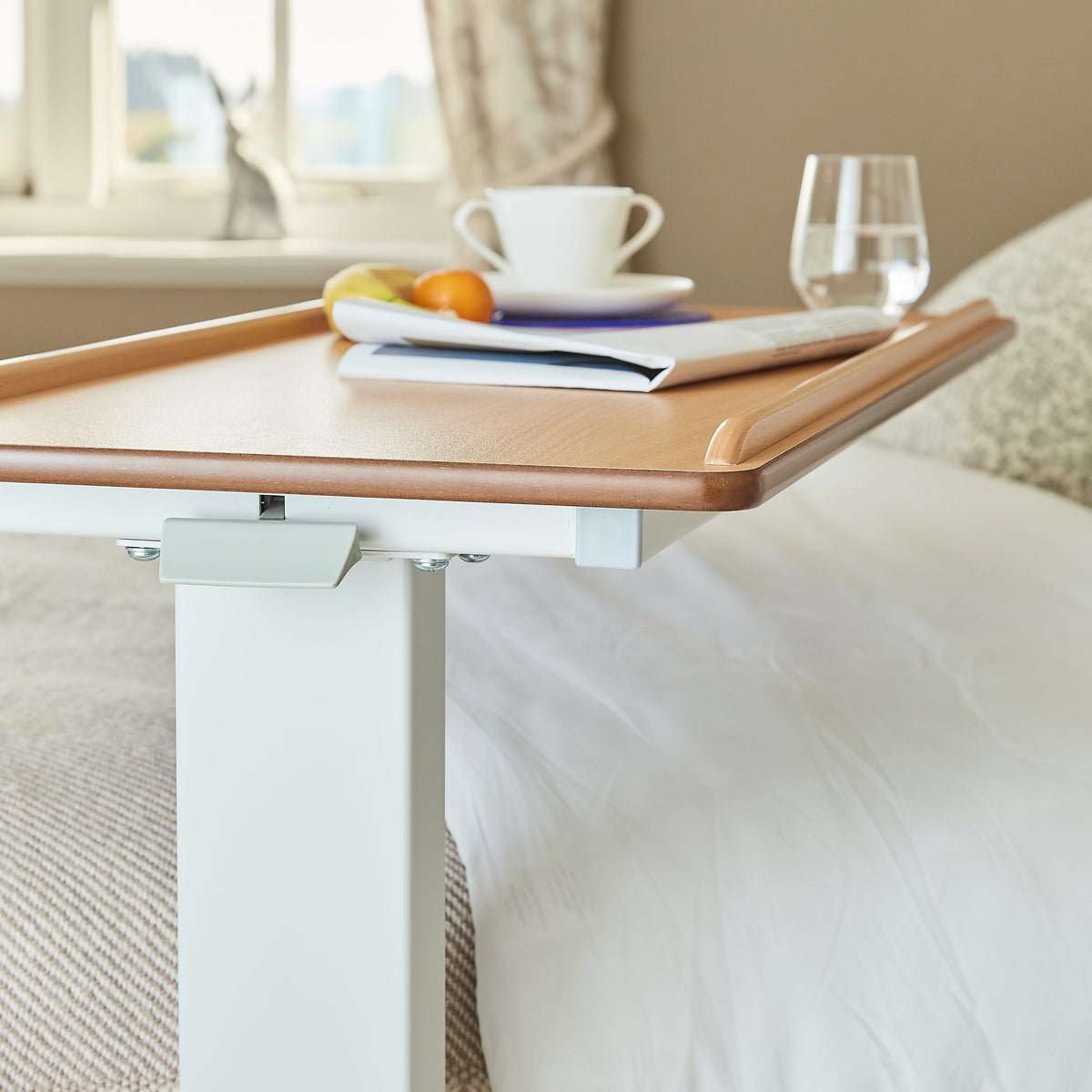 Close-up of a push button or knob on NRS Easylift Overbed Table-Low's frame used for adjusting height or tilt.