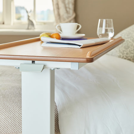 Close-up of a push button or knob on NRS Easylift Overbed Table-Low's frame used for adjusting height or tilt.