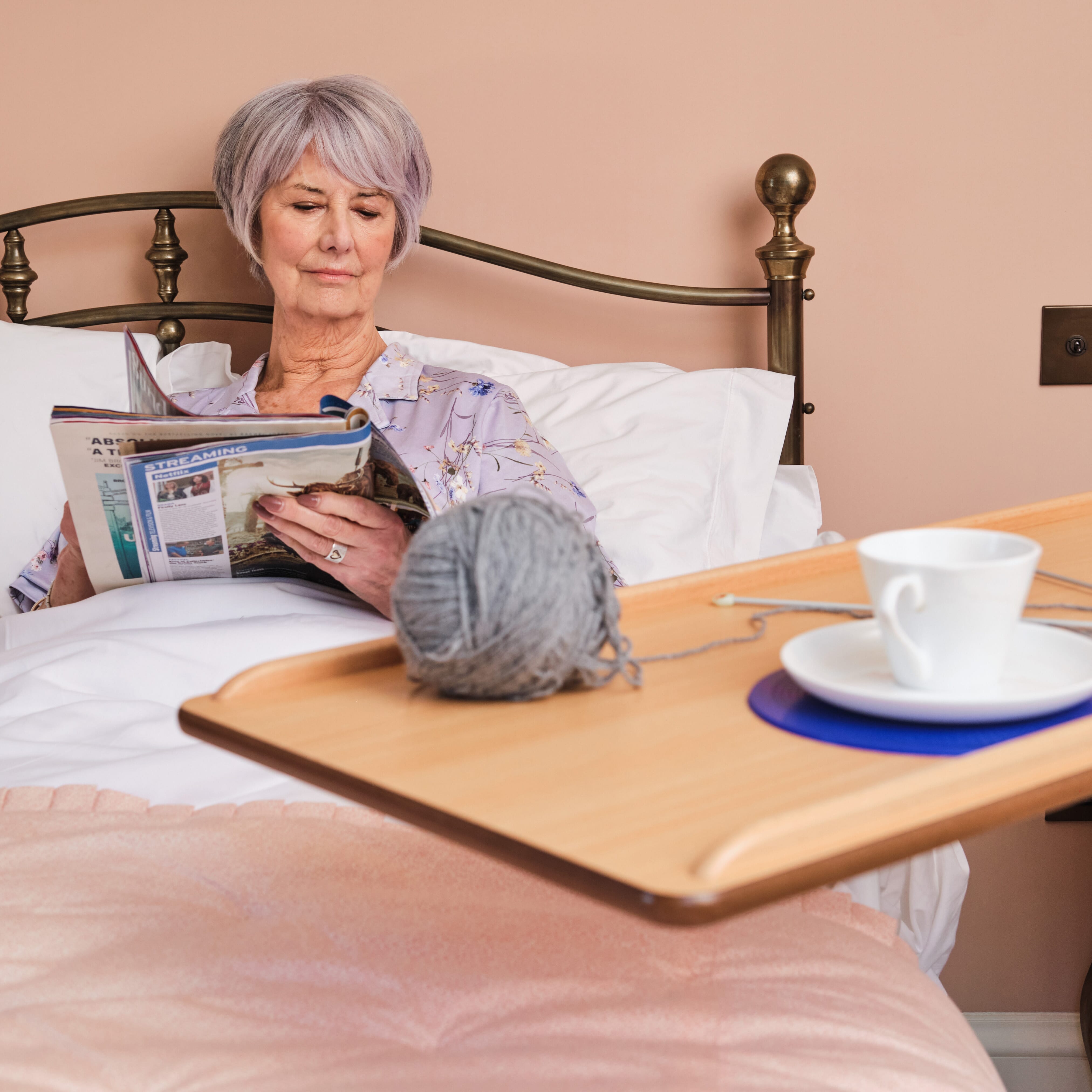 Close-up of hands adjusting the height or tilt of NRS Easylift Overbed Table, showing the easy-turn knobs.