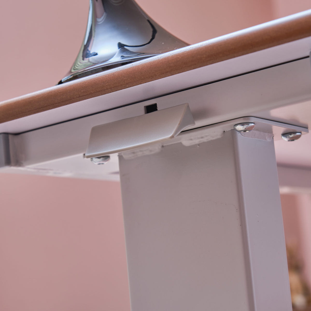 Close-up of a push button or knob on NRS Easylift Overbed Table's frame used for adjusting height or tilt.