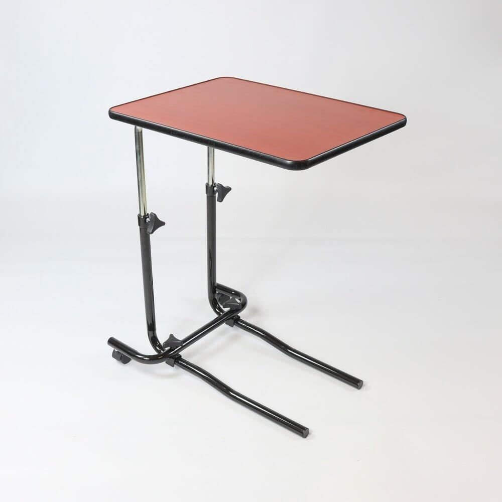 Angled view of NRS Economy Overbed Table with beech-effect tilting table top and white U-shaped base on castors against a neutral background.