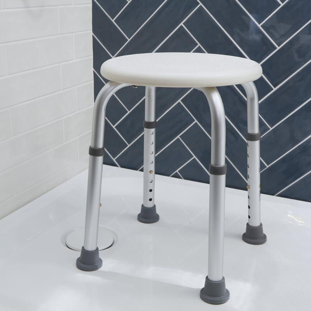 Angled view of NRS Economy Shower Stool shower stool with moulded seat and height-adjustable legs on a plain background.