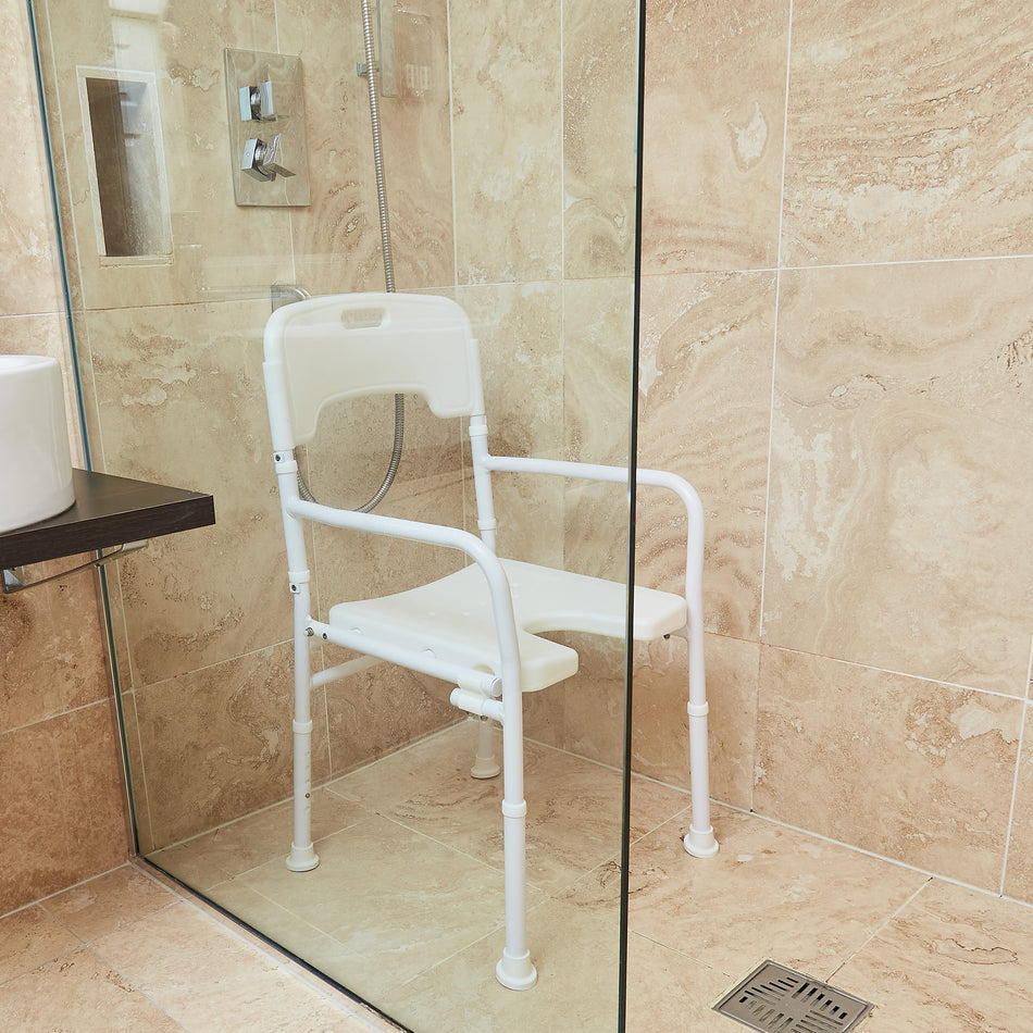 Angled view of NRS Folding Shower Chair with moulded seat, supportive backrest and height-adjustable legs on a plain background.