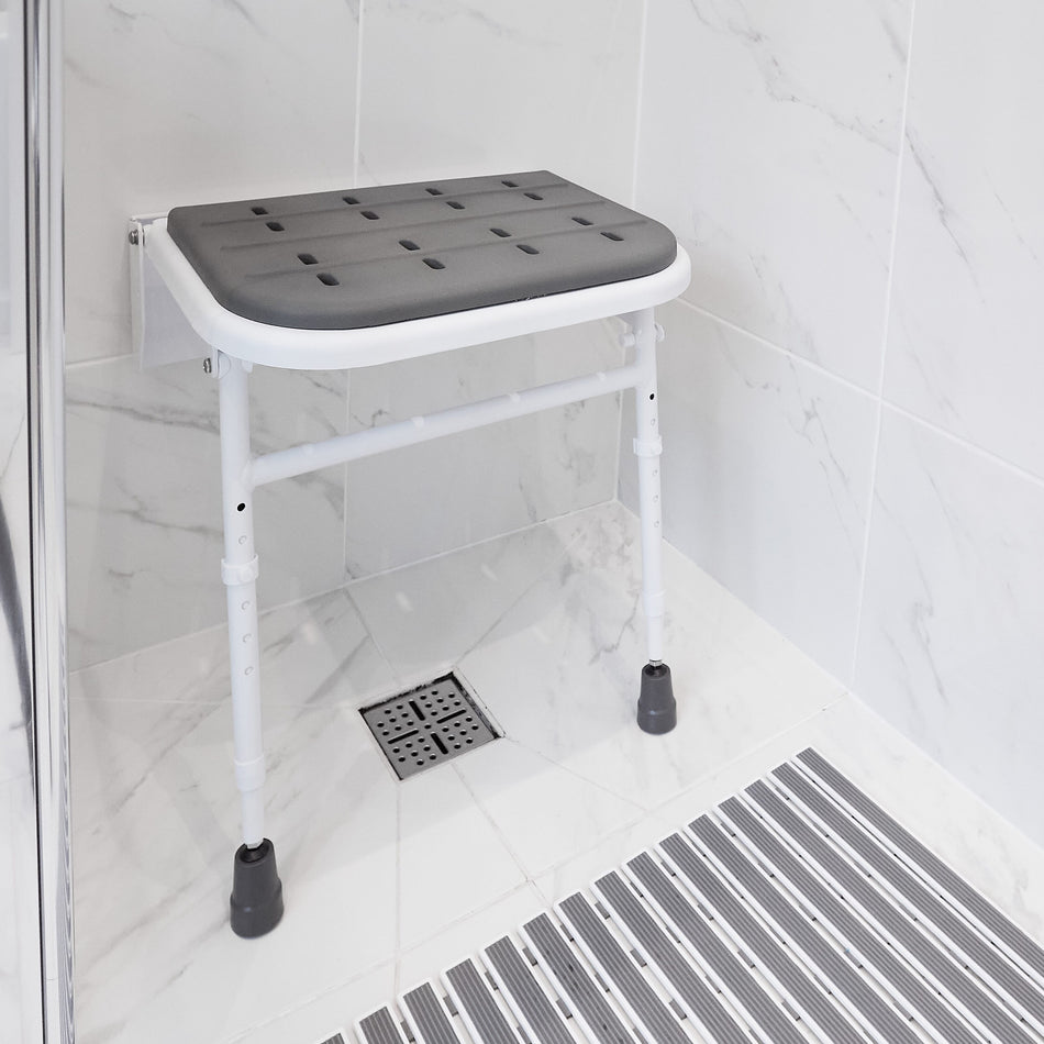 Image of NRS Folding Shower Seat with Legs and Padded Seat on a plain background.