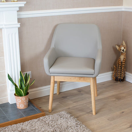 NRS Sanctuary Commode with lid raised showing the open seat and removable commode pan, with supportive arms and adjustable height on a plain background.