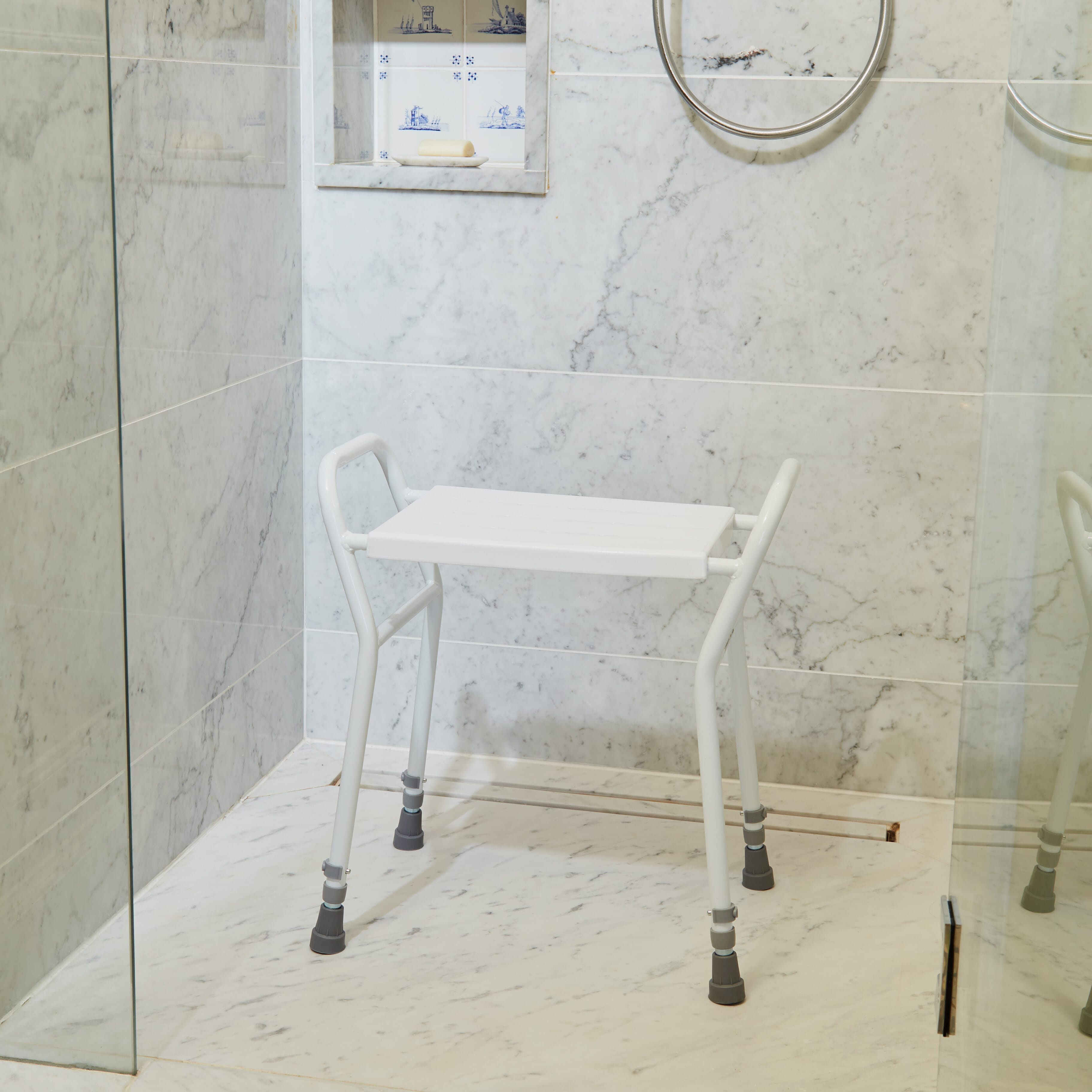 Angled view of NRS Shower Stool With Handles shower stool with moulded seat and height-adjustable legs on a plain background.