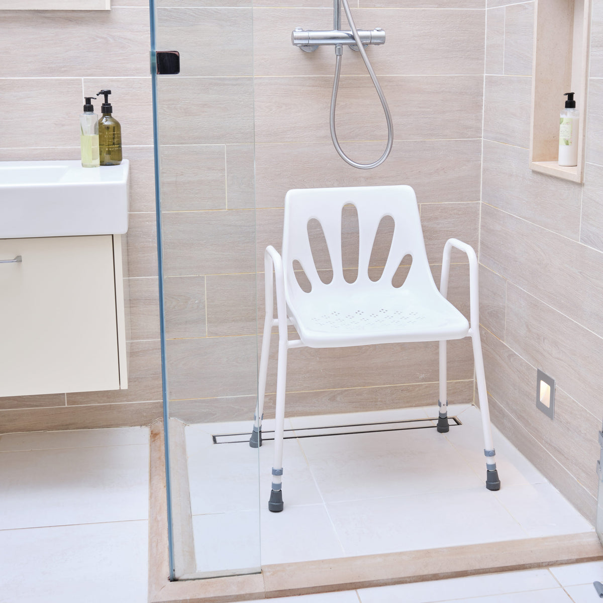 Angled view of NRS Stackable Adjustable Shower Chair with moulded seat, supportive backrest and height-adjustable legs on a plain background.