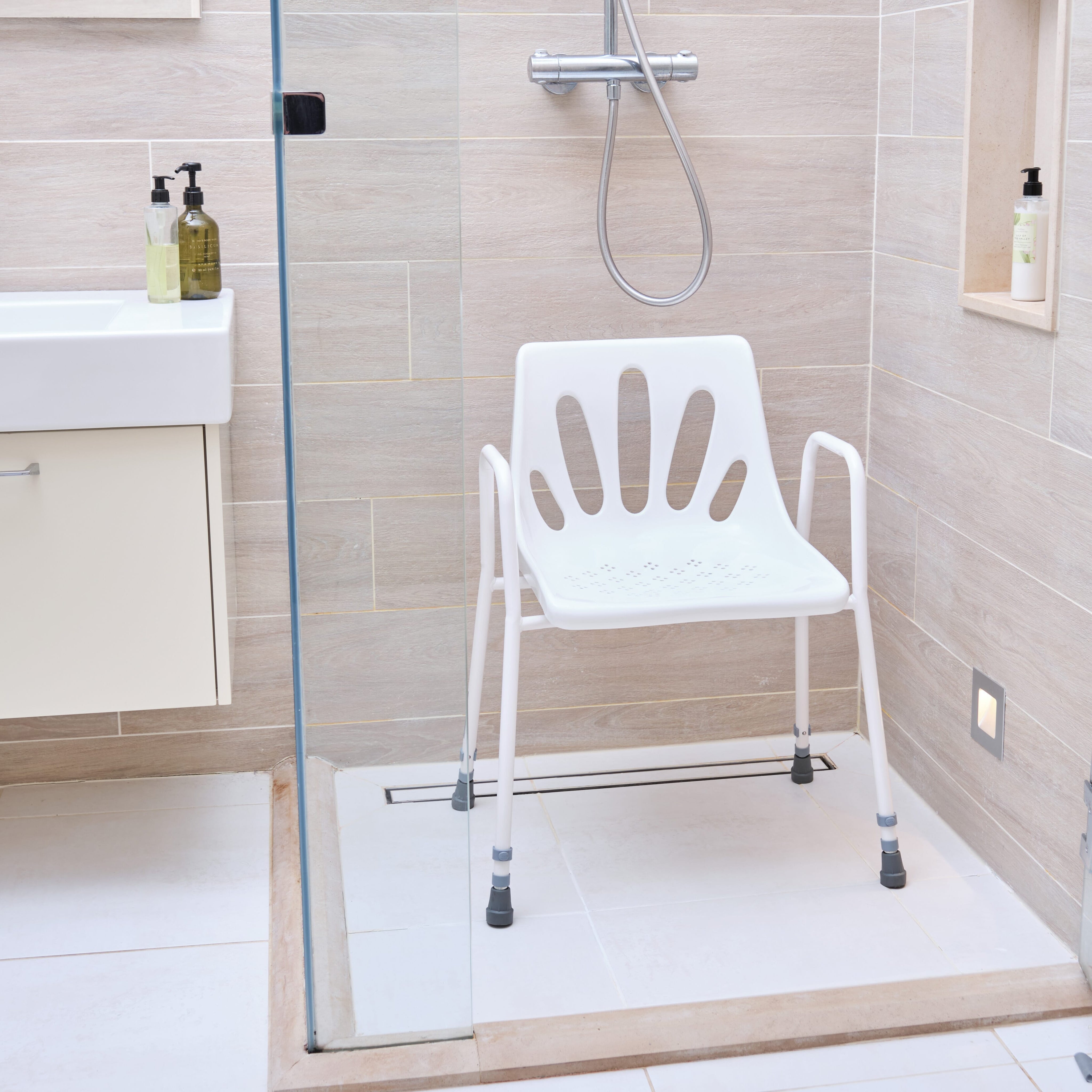 Angled view of NRS Stackable Adjustable Shower Chair with moulded seat, supportive backrest and height-adjustable legs on a plain background.