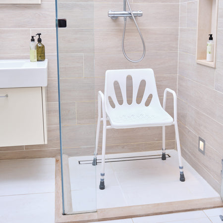 Angled view of NRS Stackable Adjustable Shower Chair with moulded seat, supportive backrest and height-adjustable legs on a plain background.