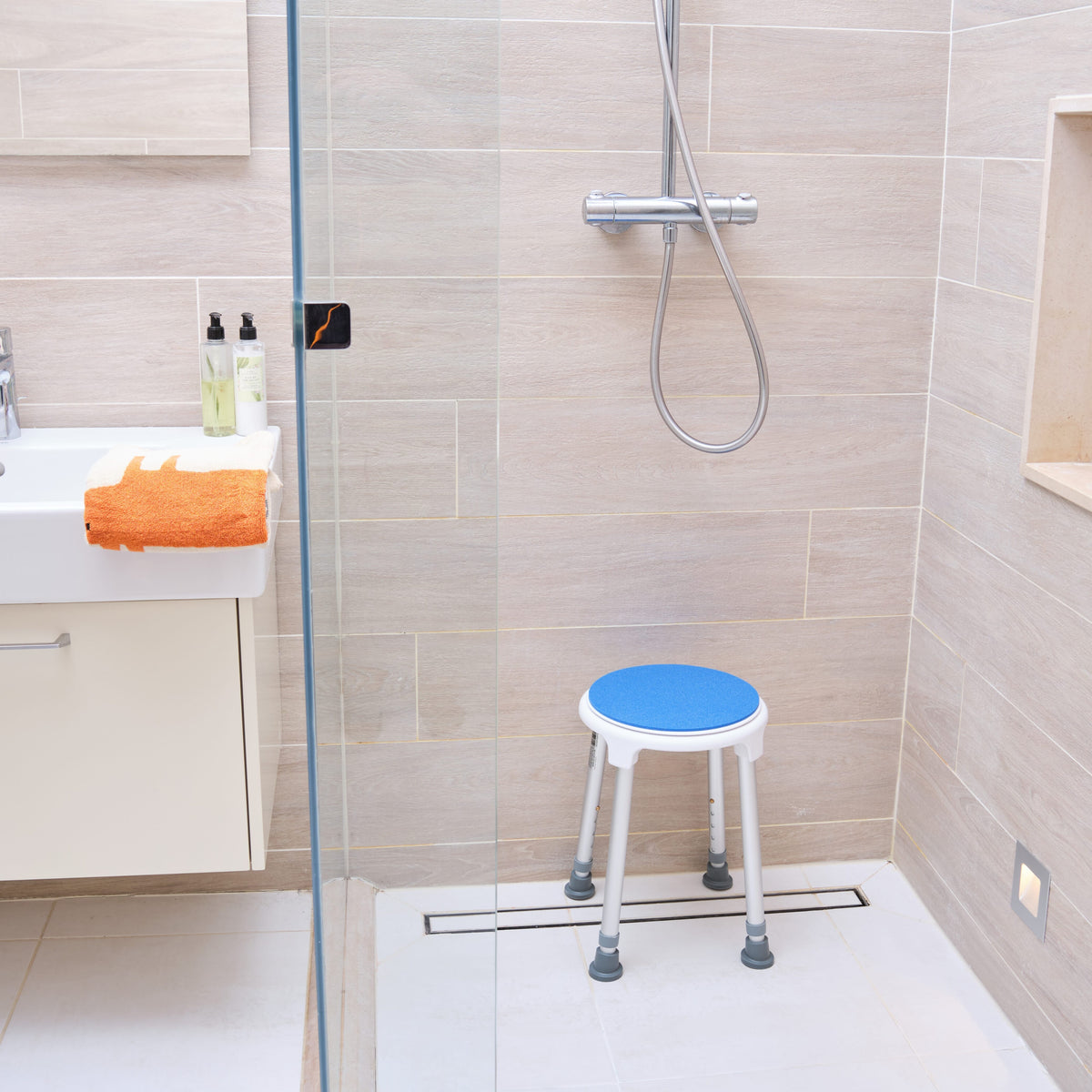 Angled view of NRS Swivel Shower Stool shower stool with moulded seat and height-adjustable legs on a plain background.