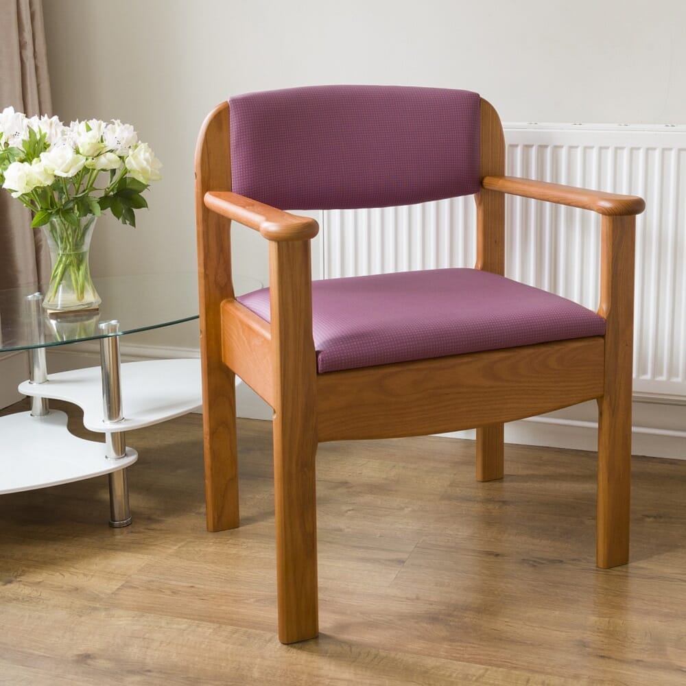 Royale Extra Wide Commode Chair with lid raised showing the open seat and removable commode pan, with supportive arms and adjustable height on a plain background.