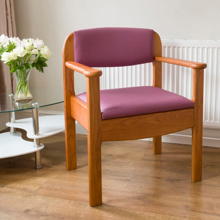 Royale Extra Wide Commode Chair with lid raised showing the open seat and removable commode pan, with supportive arms and adjustable height on a plain background.