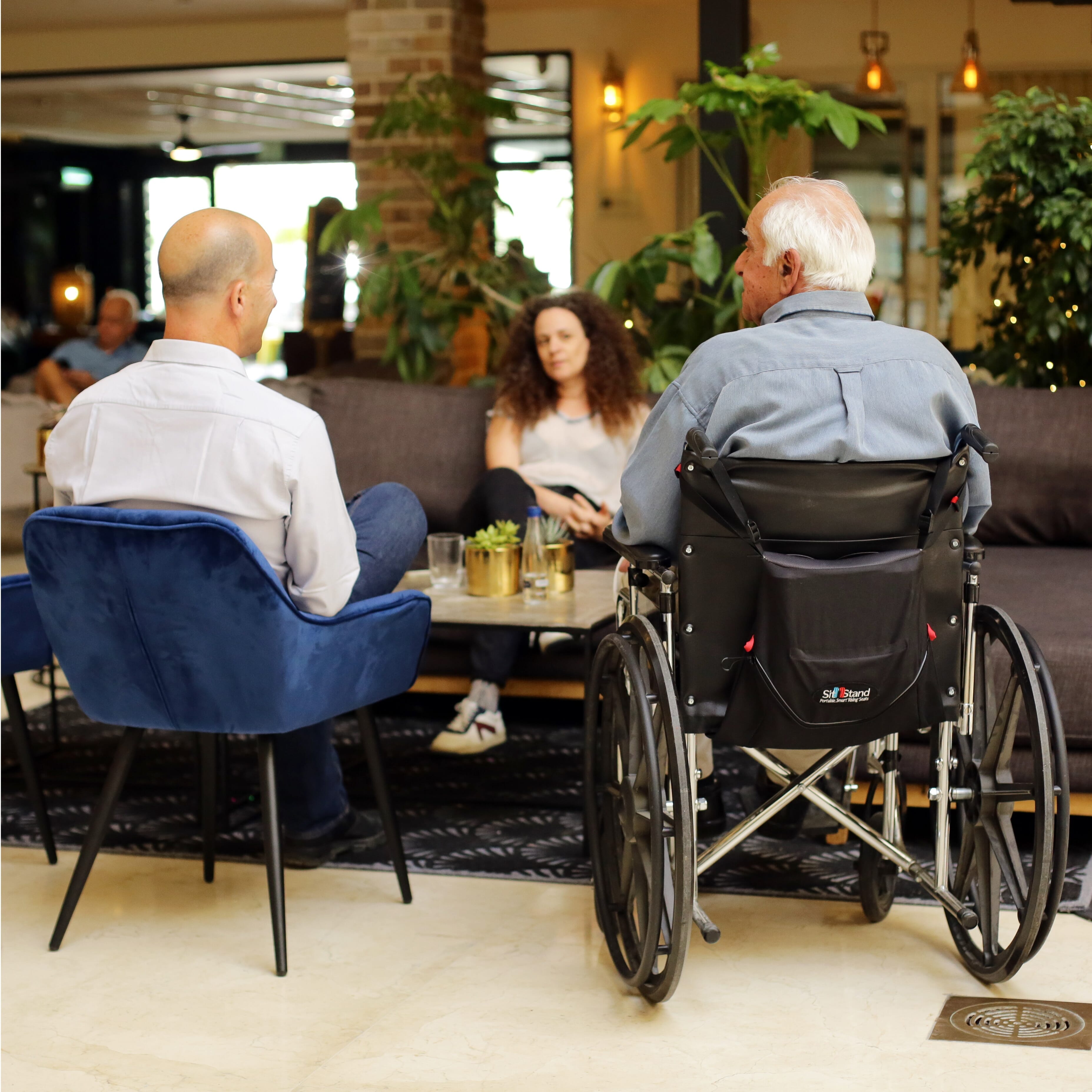 Lifestyle image of SitnStand Portable Rising Seat For Wheelchairs being used in a real-life setting.